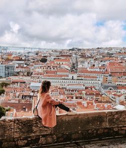 Rear view of woman standing against buildings in city