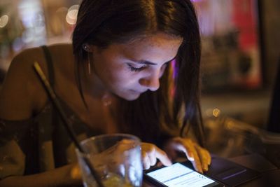 Close-up of young woman using phone while sitting on table