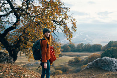 Portrait of smiling young woman standing against trees