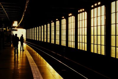 Silhouette of people standing on railroad station platform