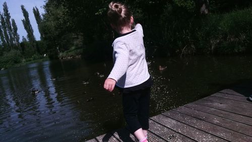 Rear view of woman standing by lake