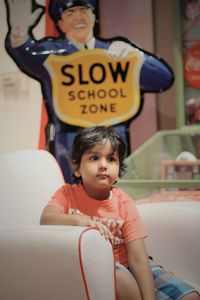 Boy looking away while sitting on armchair in school