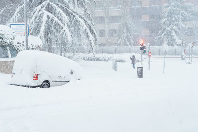 People on snow covered street in city