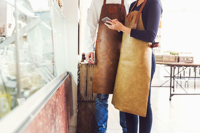 Midsection of owners using digital tablet in grocery store