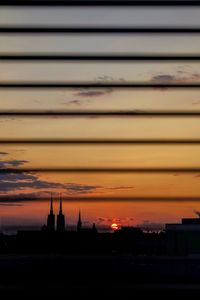 Silhouette of city against dramatic sky during sunset