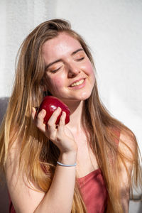 Young woman with eyes closed holding apple