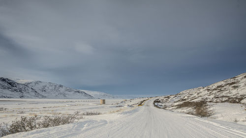 Road amidst snow covered landscape against sky