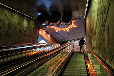 Rear view of man on escalator at subway station