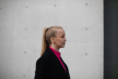 Portrait of young woman looking away against wall