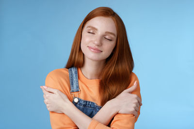 Portrait of smiling young woman against blue background