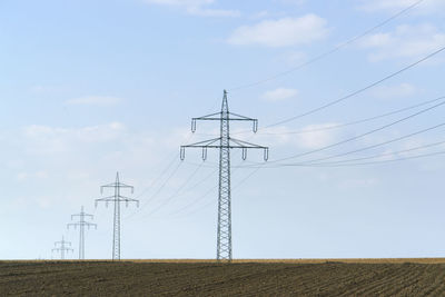 Low angle view of electricity pylon on field against sky