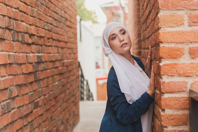 Young woman standing by brick wall