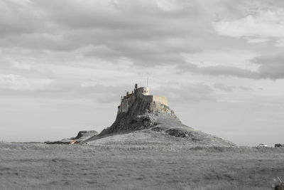 View of lighthouse on landscape against cloudy sky