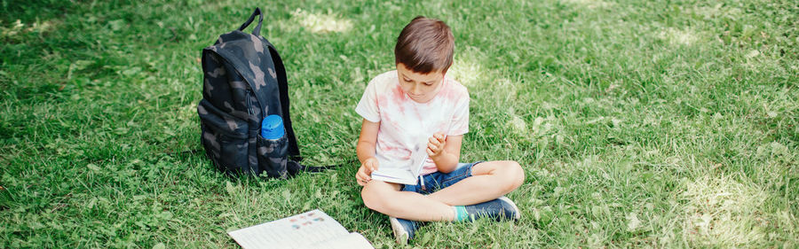 High angle view of boy sitting on grass at park