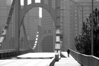 Man walking in sidewalk on bridge