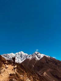 Man standing on mountain against clear blue sky