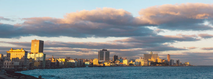 City at waterfront against cloudy sky