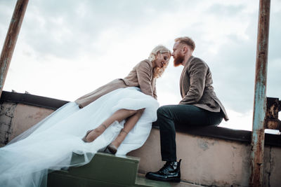 Rear view of couple sitting against sky