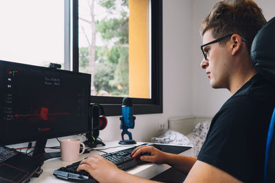 Side view of man using laptop at office