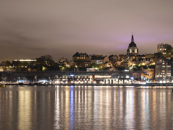 Cityscape view of södermalm stockholm during cloudy night with light reflections in the water.