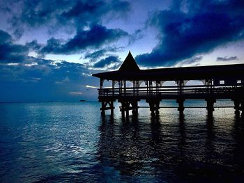 Silhouette built structure by sea against sky