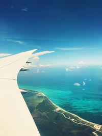 Aerial view of airplane wing over sea against blue sky