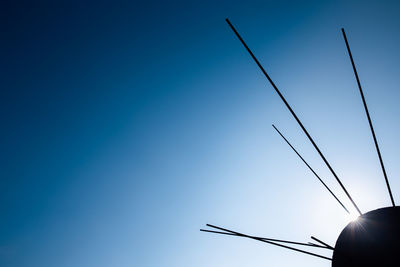 Low angle view of silhouette power lines against clear blue sky