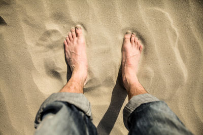 Low section of man standing on sand