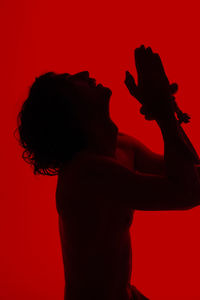 Side view of silhouette man against red background