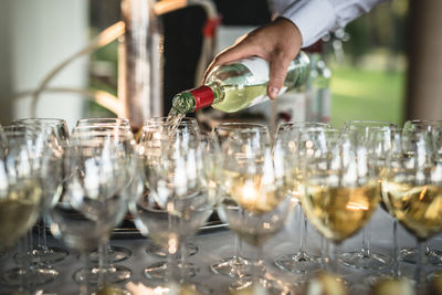 Cropped hand pouring wine in glasses on table