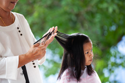 Close-up of girl with arms raised standing outdoors