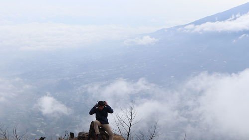 Low angle view of man photographing mountains against sky