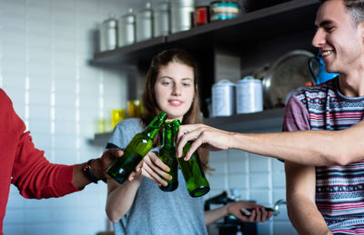 Friends toasting beer bottles at home