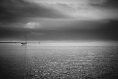 Boat sailing in sea against cloudy sky