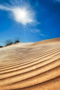 Sand dunes in desert against blue sky