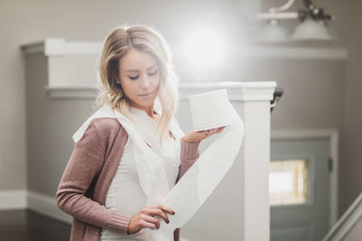 Beautiful young woman standing against wall at home