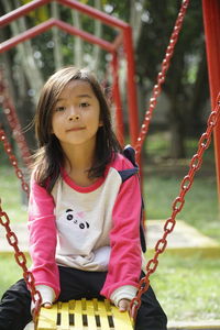 Portrait of a smiling girl on swing in playground