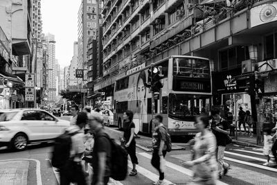 People walking on road by buildings in city