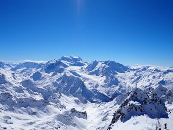 Scenic view of snow covered mountains against clear blue sky