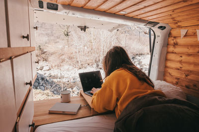 Woman using phone while sitting on table