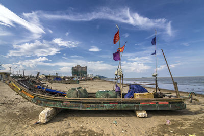 Fishing boat on beach against sky