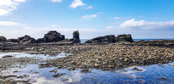 Rock formations in sea against sky during winter