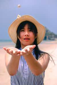 Young woman catching seashells while standing at beach