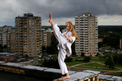 Woman practicing martial arts on retaining wall of building terrace