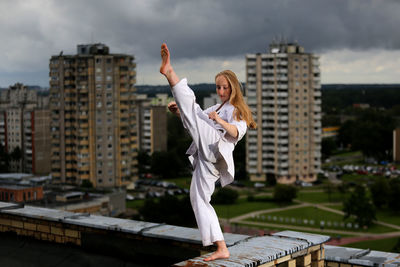 Woman with arms outstretched against buildings