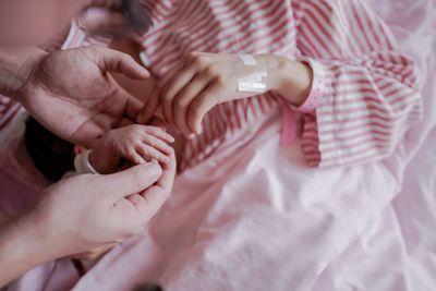 High angle view of couple hands on bed