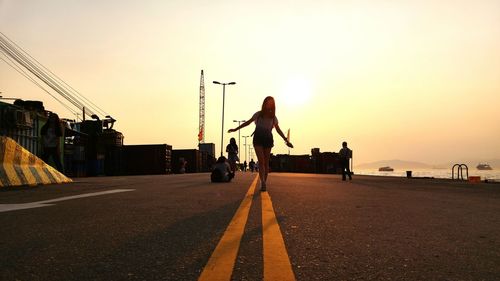 Rear view of man skateboarding on road