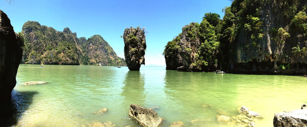 water, tree, tranquil scene, tranquility, scenics, beauty in nature, clear sky, nature, lake, blue, idyllic, rock - object, sky, reflection, mountain, day, waterfront, non-urban scene, forest, no people