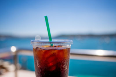 Close-up of drink in disposable glass against sea