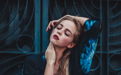 Young woman with eyes closed against gate